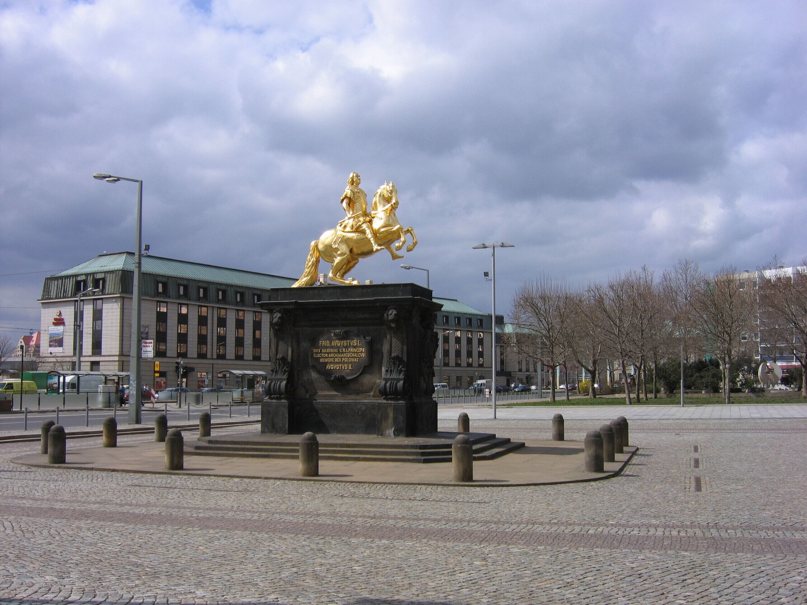 Una statua dorata di un uomo a cavallo in una piazza pubblica, con un edificio sullo sfondo.