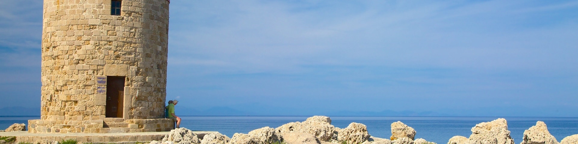 Un faro de piedra con techo rojo a orillas del mar.