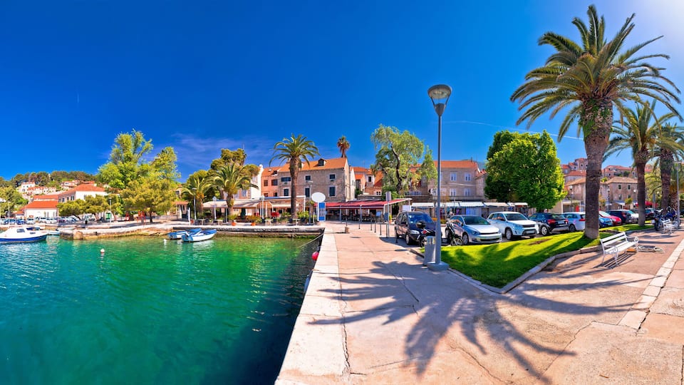 A coastal town with a marina, palm trees, and historic buildings along the waterfront.