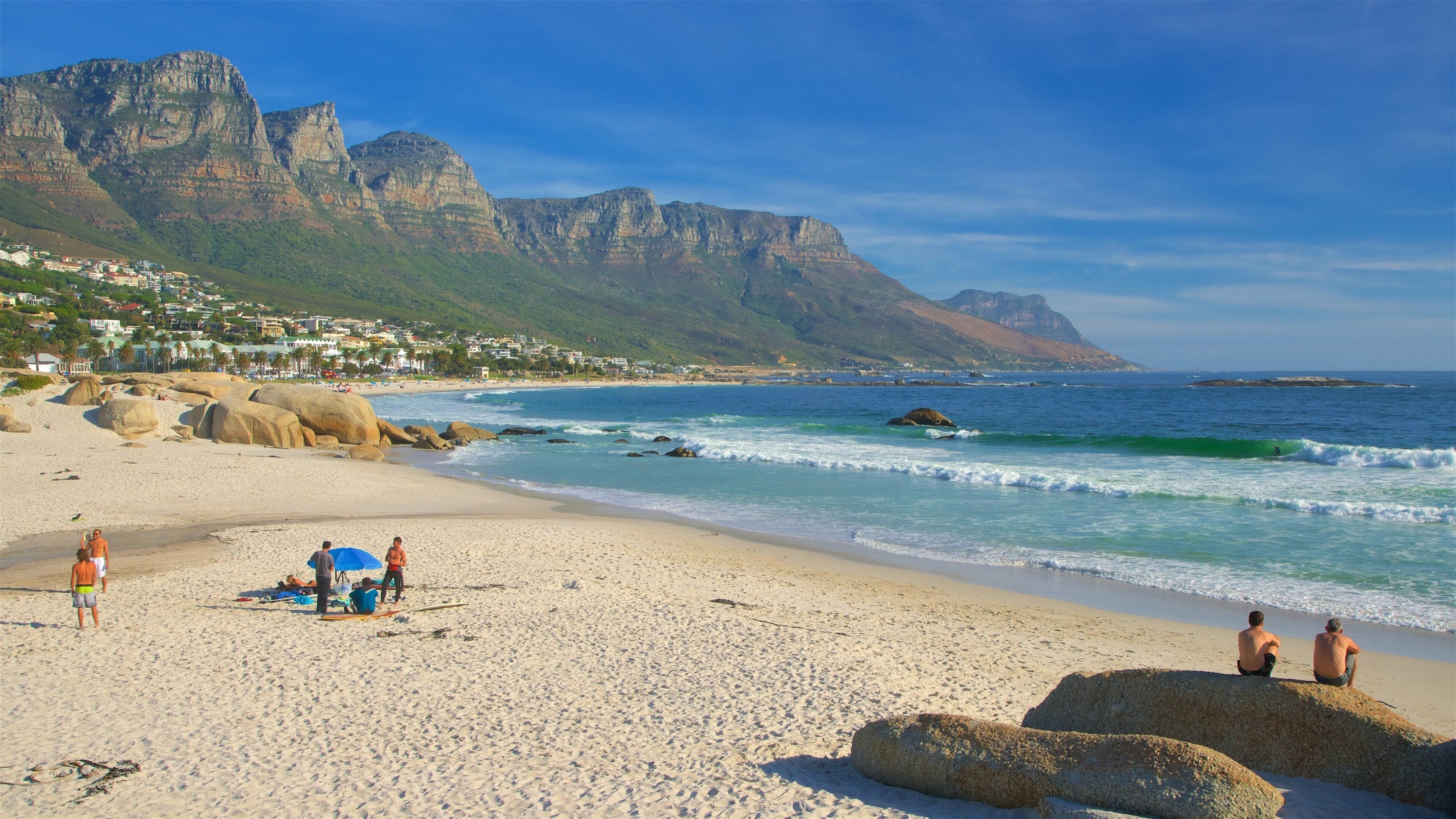 Camps Bay Beach showing a coastal town and a sandy beach as well as a small group of people