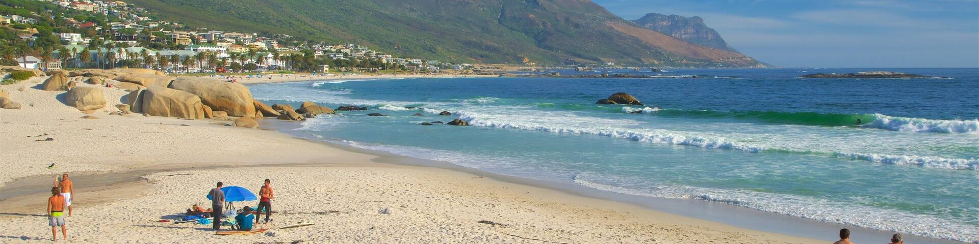 Une plage avec de gros rochers, des vagues et une montagne en arrière-plan.