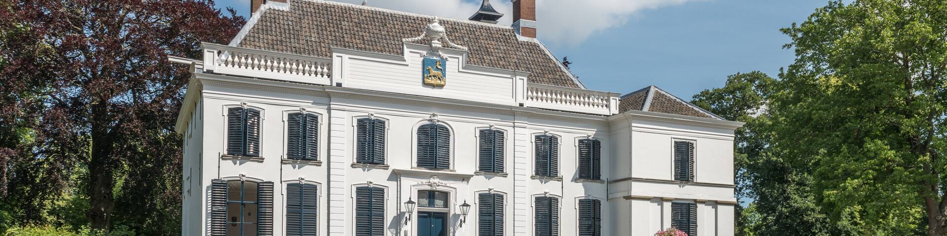 Historic Dutch mansion with trees, blue sky and white clouds