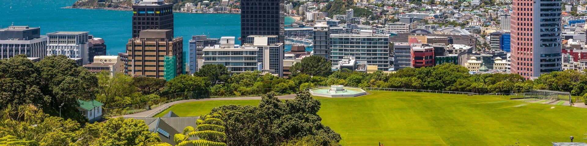 A coastal cityscape with a clear view of the ocean, mountains in the background, and a mix of modern and traditional buildings.