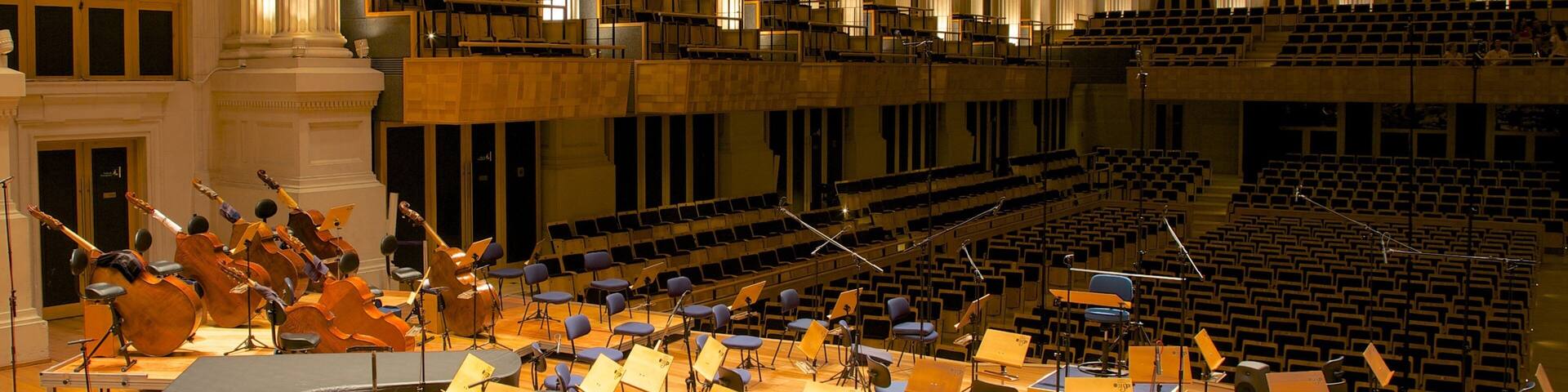 Una orquesta en un salón amplio con techos altos y columnas.