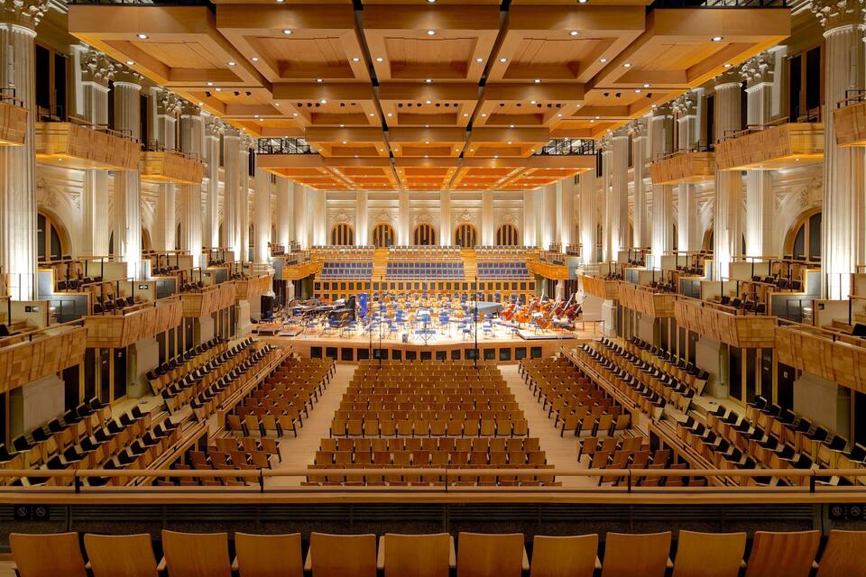 Una gran sala de concerts ornamentada, amb seients escalonats i un escenari central.