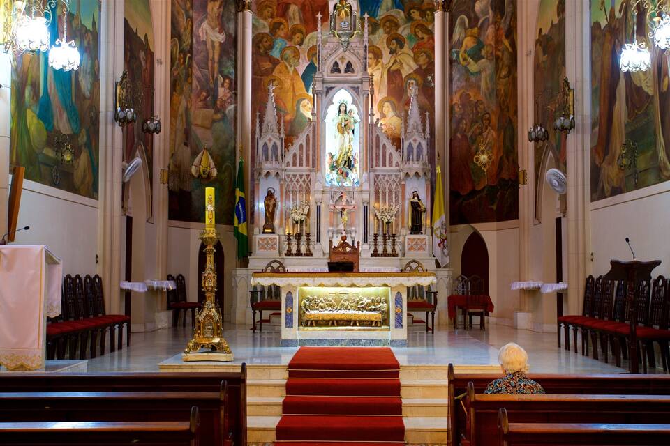 An ornate church interior with a central altar, religious statues, and a large mural on the walls.