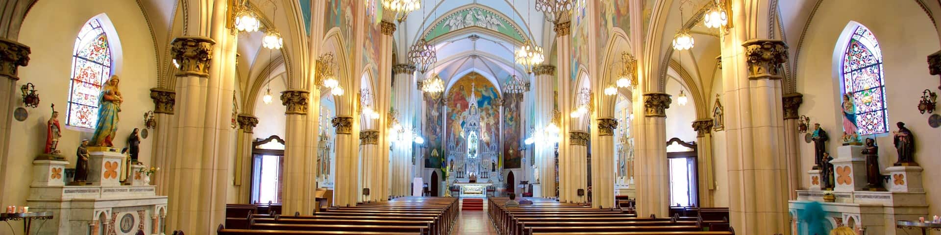 A church interior with rows of pews, stained glass windows, and a central altar.
