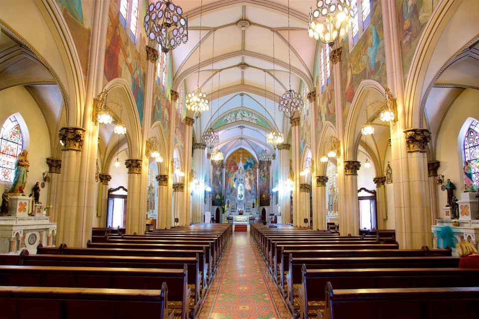 Interior d'una església amb files de bancs, vitralls i un altar central.