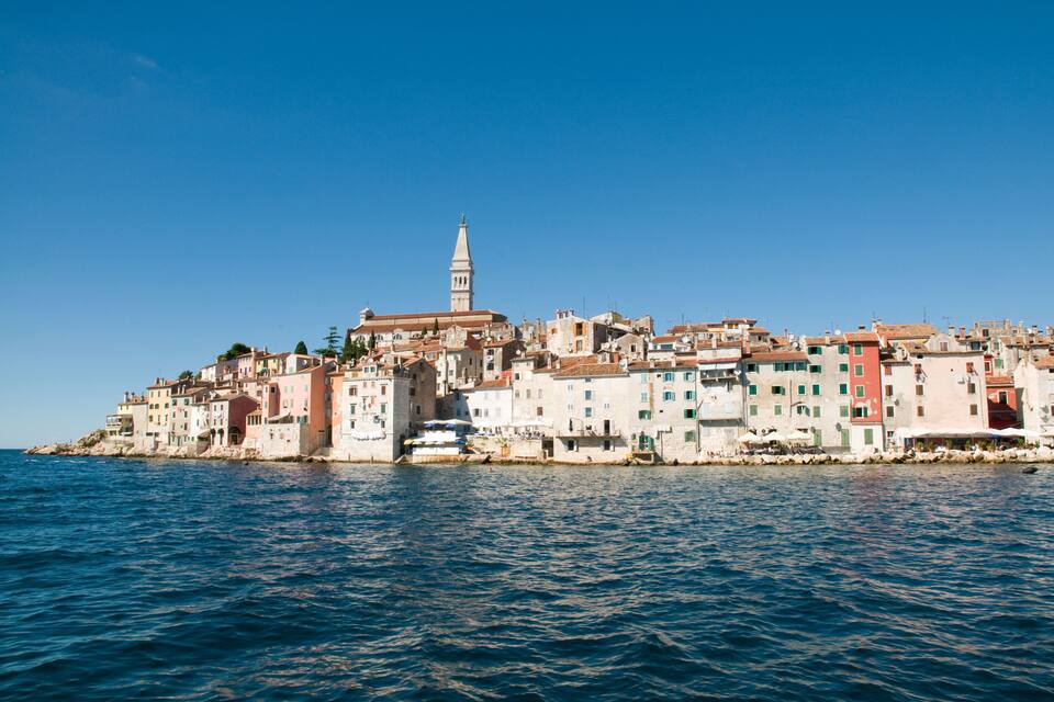 A coastal town with colorful buildings and a prominent tower.