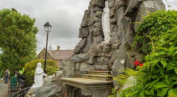 A stone structure with a statue, a bench, and a lamppost.