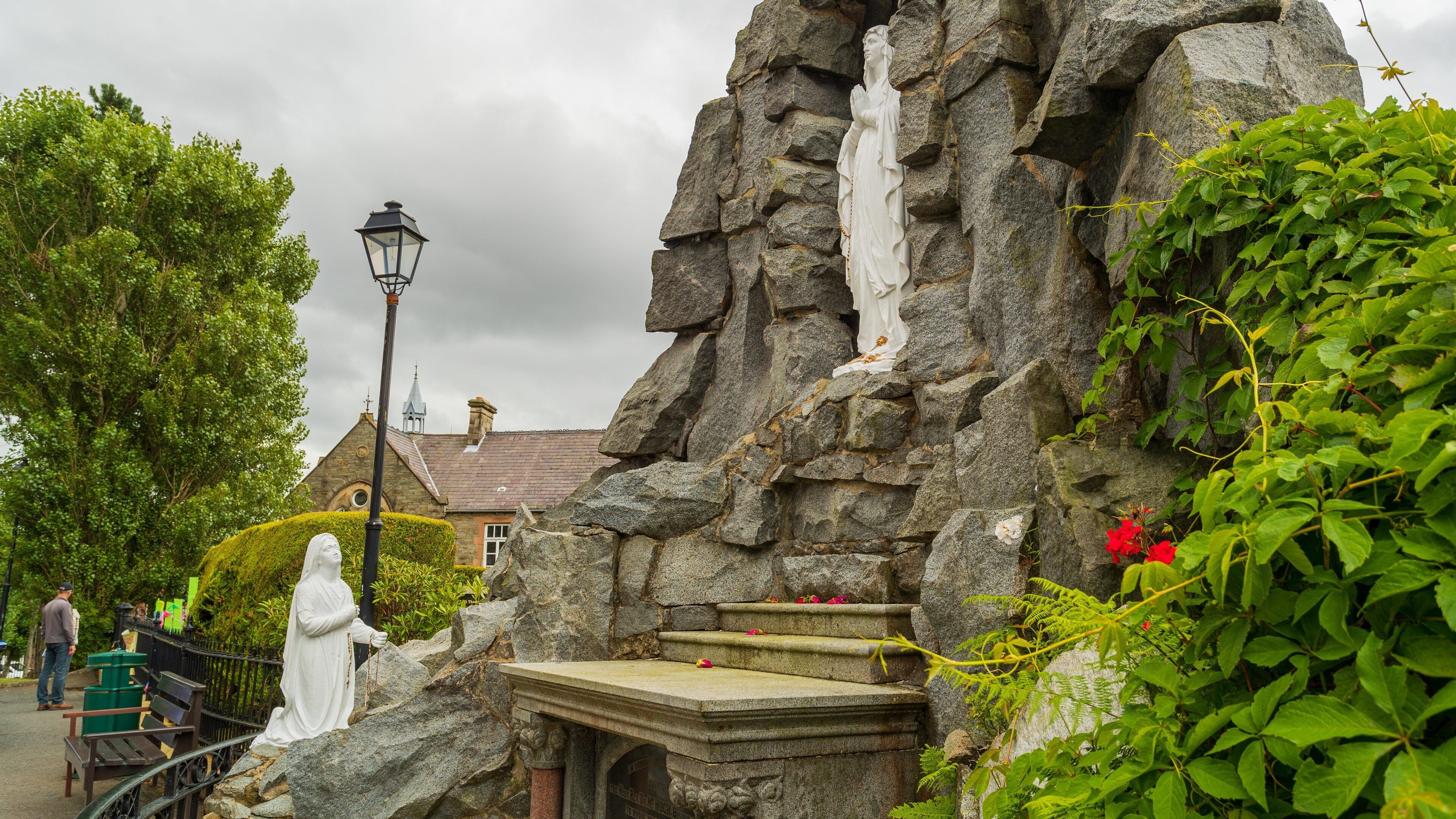A stone structure with a statue, a bench, and a lamppost.