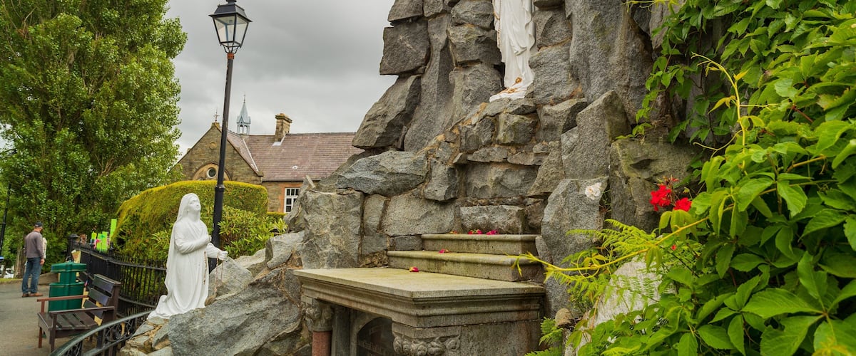 A stone structure with a statue, a bench, and a lamppost.