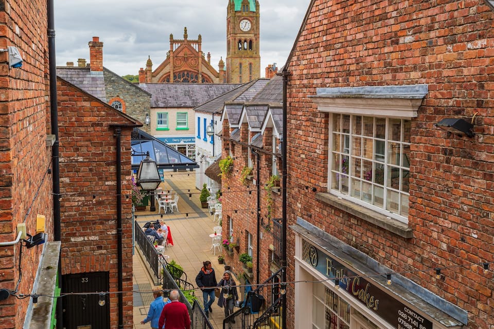 A narrow street with brick buildings, a clock tower, and a pub named 'Funky Cakes'.