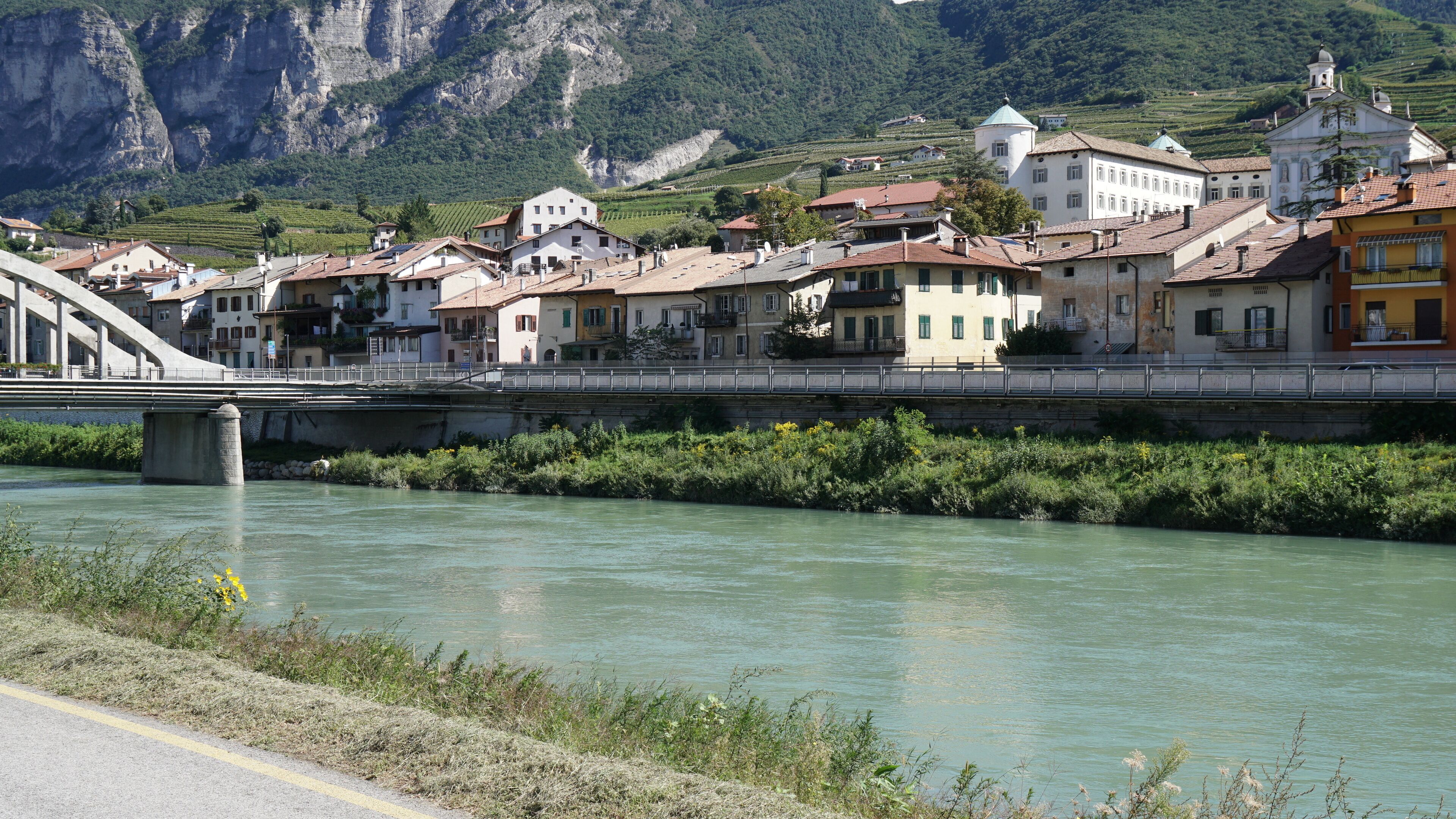 A river with a bridge, buildings, and mountains in the background.