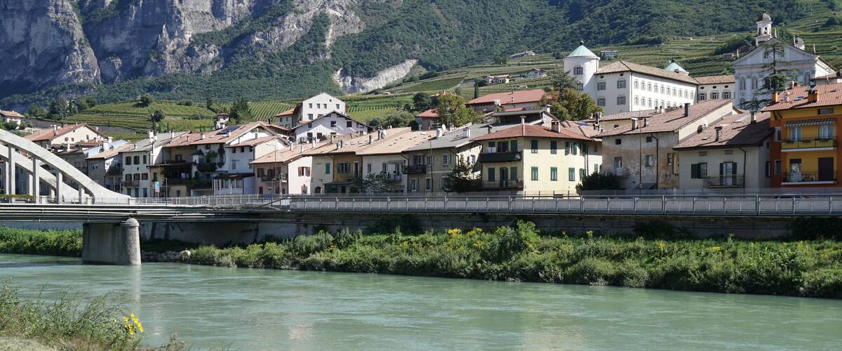 A river with a bridge, buildings, and mountains in the background.
