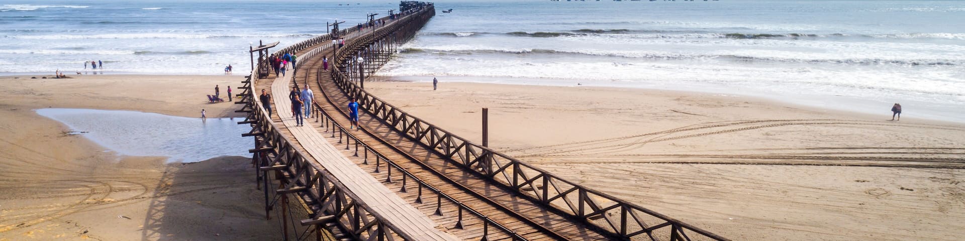 A wooden boardwalk extending into the ocean, with people walking along it.