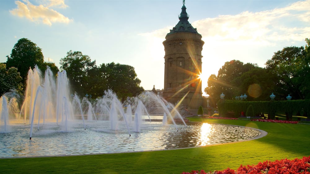 Une fontaine, une tour et un coucher de soleil.