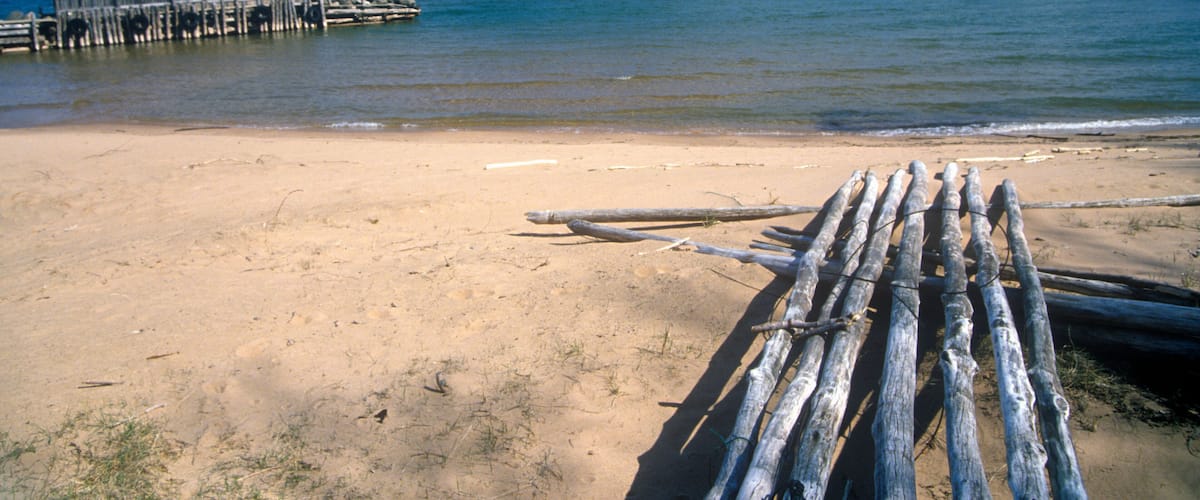 A sandy beach with a wooden structure extending into the water.