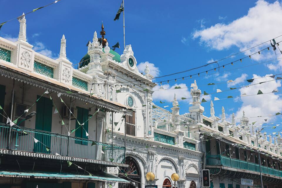Un edifici blanc amb detalls ornamentals i accents verd, amb un penó.