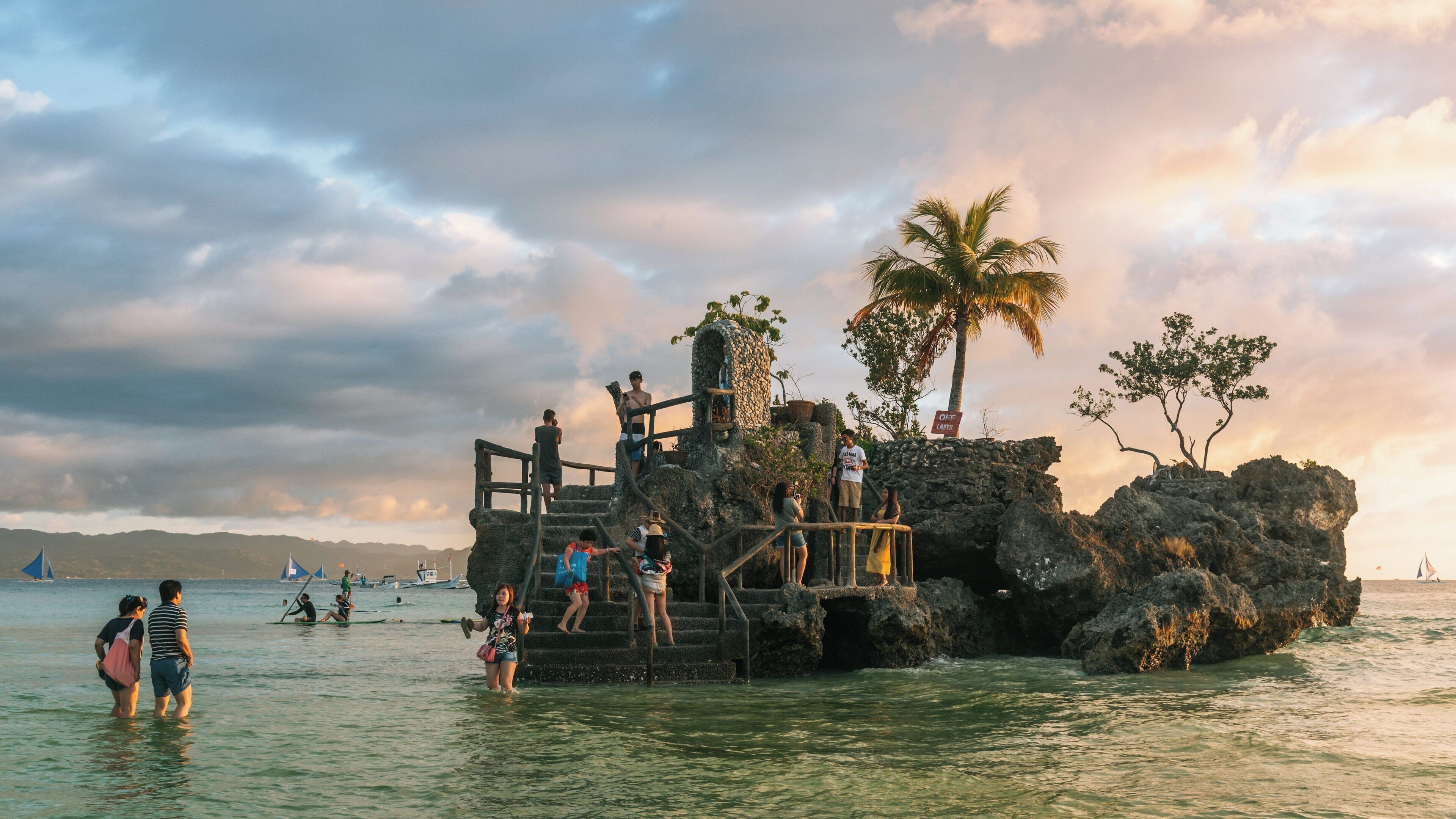 Visitors enjoy the sunset at Willy's Rock on Boracay Island in the Philippines while exploring the surrounding waters and beach activities