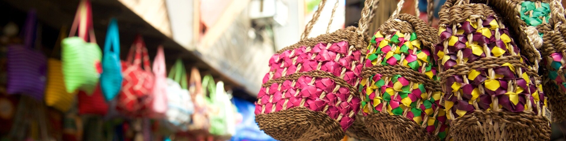 Bolsas tejidas de colores colgando en un mercado.