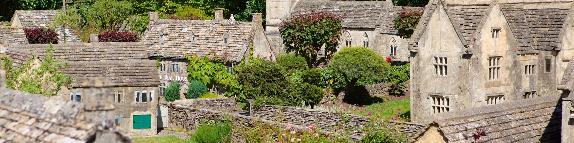 A model village with stone buildings, a church tower, and lush greenery.