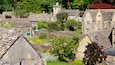 A model village with stone buildings, a church tower, and lush greenery.