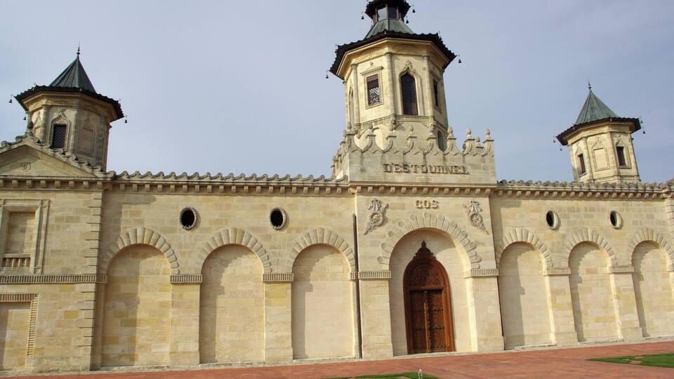 A historic building with two bell towers, arched doorways, and a central tower with inscriptions.