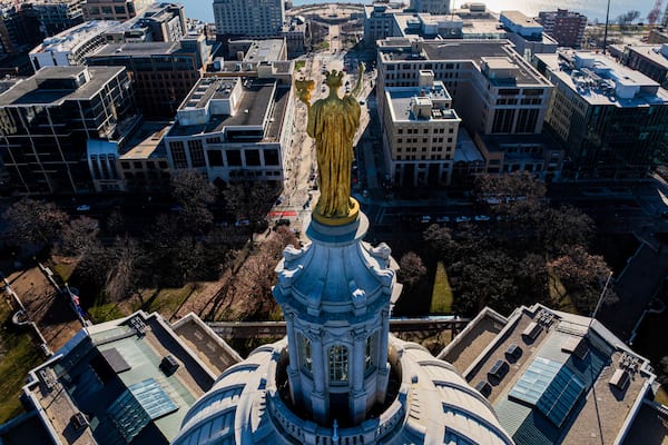 A cityscape with a prominent golden statue atop a classical building.