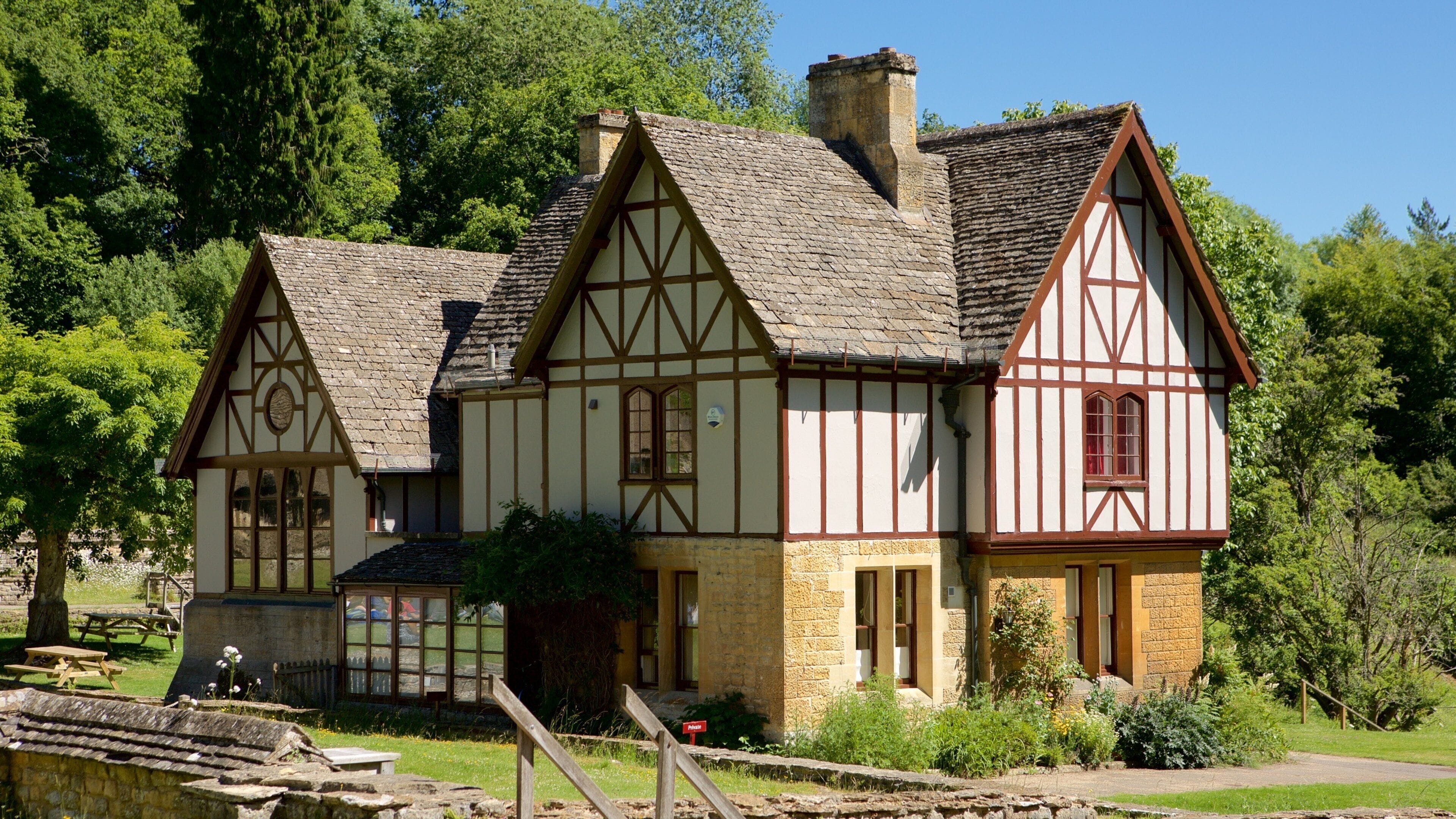 Ein Haus im Tudor-Stil mit Stein Fundament und Fachwerkkonstruktion, umgeben von üppiger Vegetation.