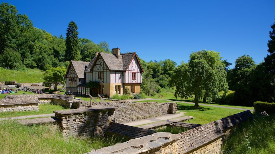 A Tudor-style house surrounded by stone walls and lush greenery.