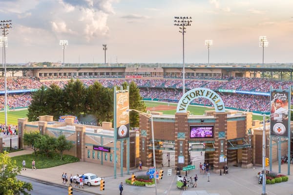 A baseball stadium with a large crowd, a prominent arch with "VICTORY FIELD" written on it, and a "Star Wars" advertisement on the scoreboard.