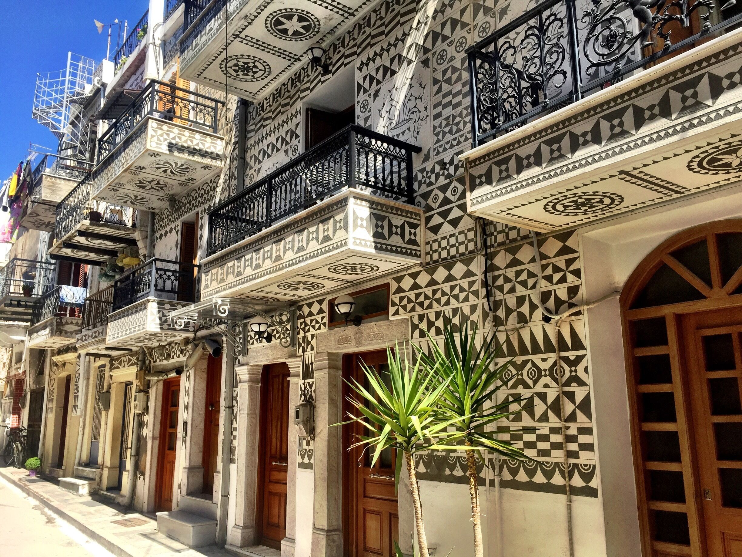A row of buildings with intricate geometric tile patterns and balconies with wrought iron railings.
