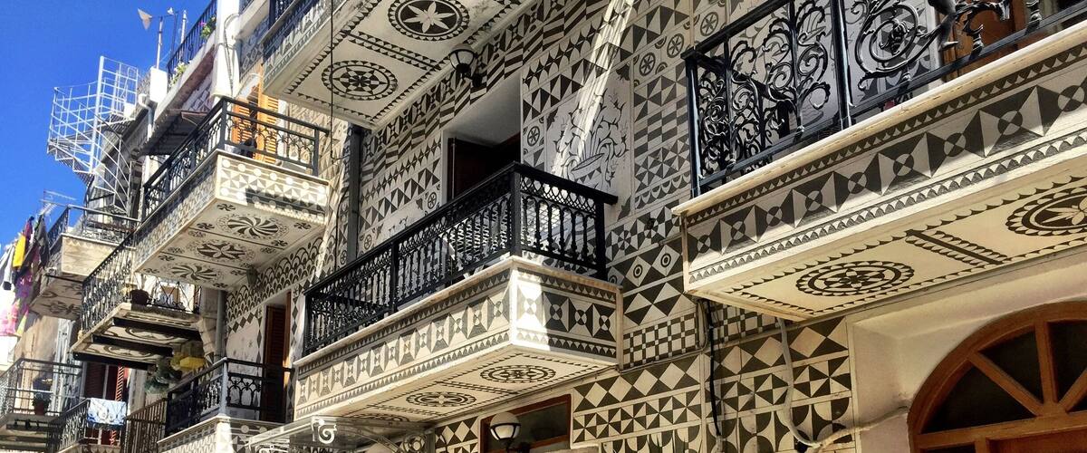 A row of buildings with intricate geometric tile patterns and balconies with wrought iron railings.
