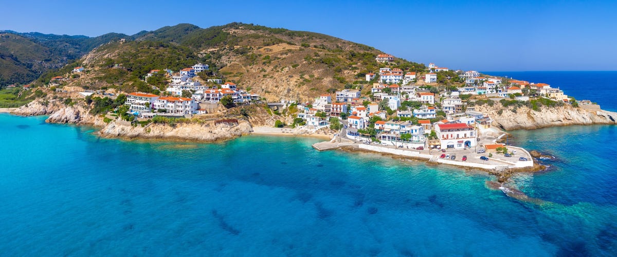 Lovely greek fishing village of Armenistis in a quiet summer morning. Port with local beach in transparent clear water at Ikaria, Greece