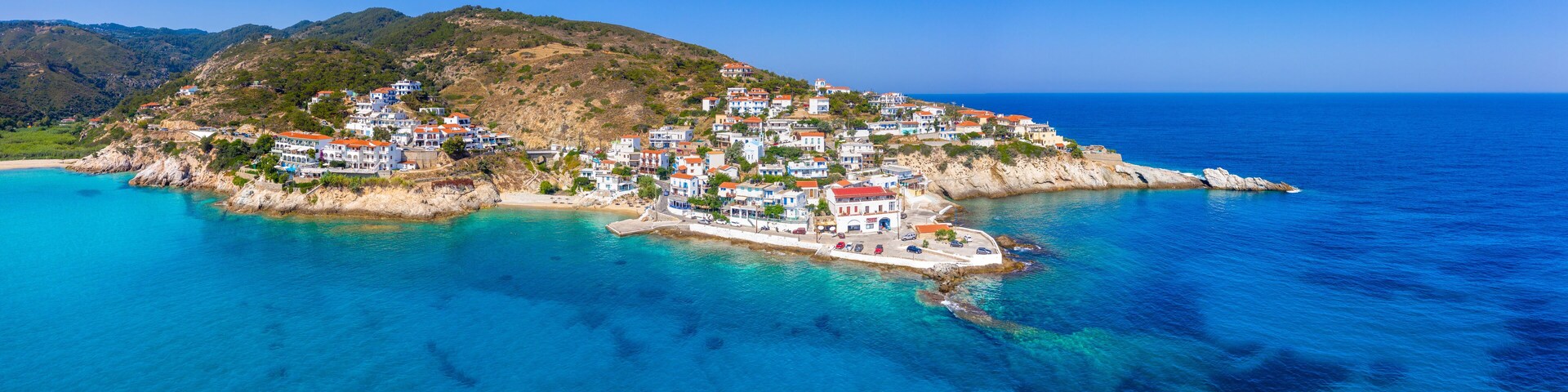 Lovely greek fishing village of Armenistis in a quiet summer morning. Port with local beach in transparent clear water at Ikaria, Greece