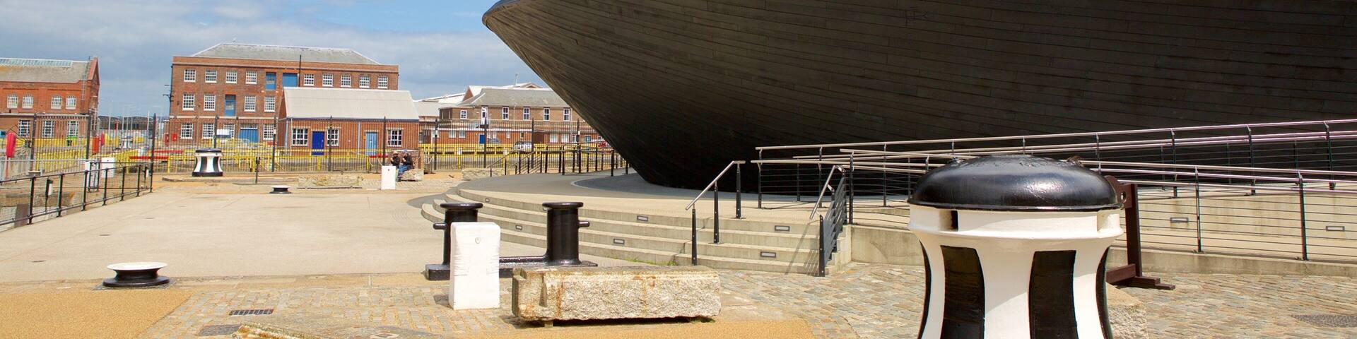 A modern architectural structure with a curved facade, a stone bollard, and a paved walkway.