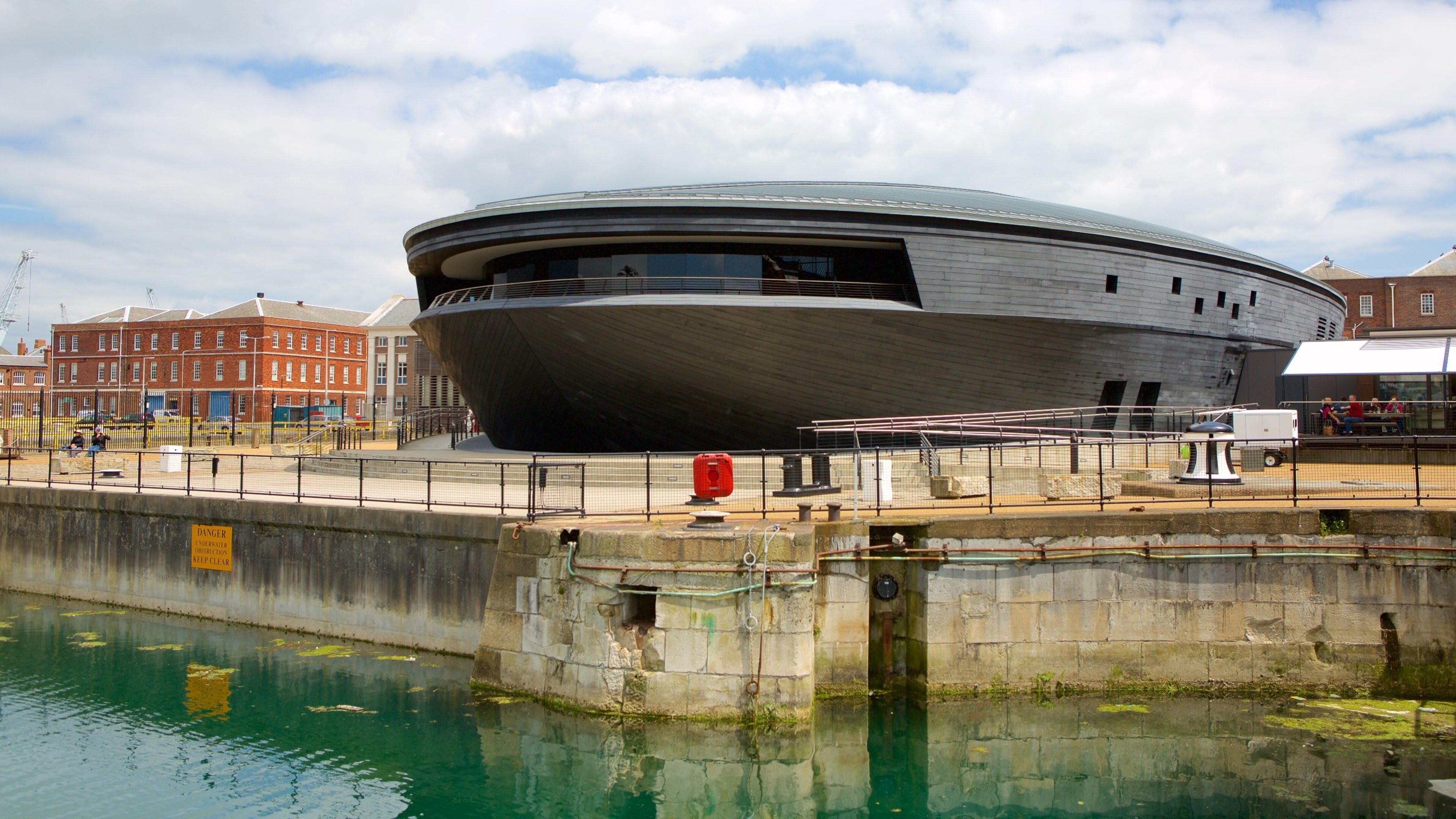 Een groot, rond gebouw met een modern ontwerp, gelegen aan een waterpartij.