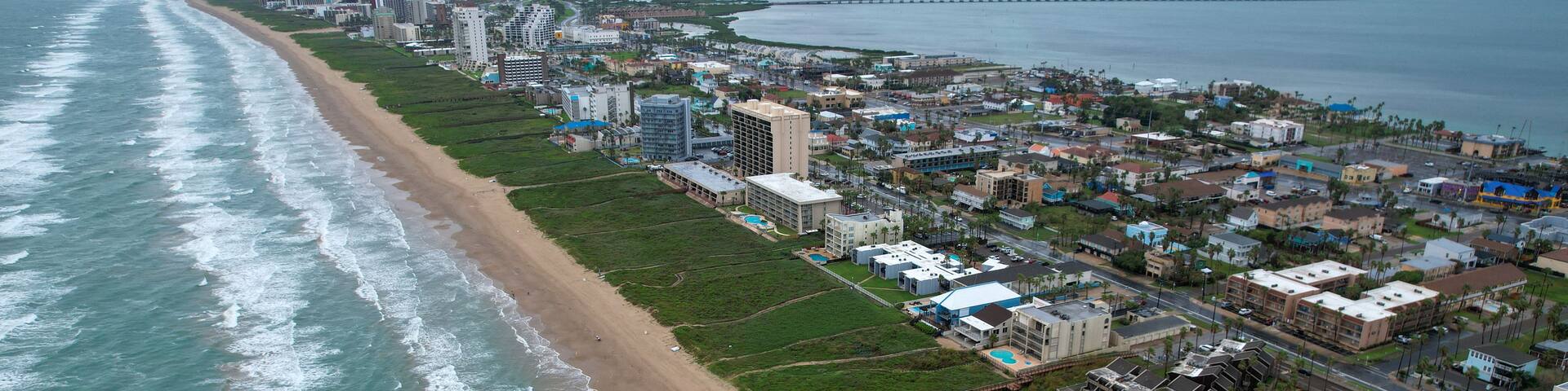 Un paisaje urbano costero con playa, edificios y un puente.