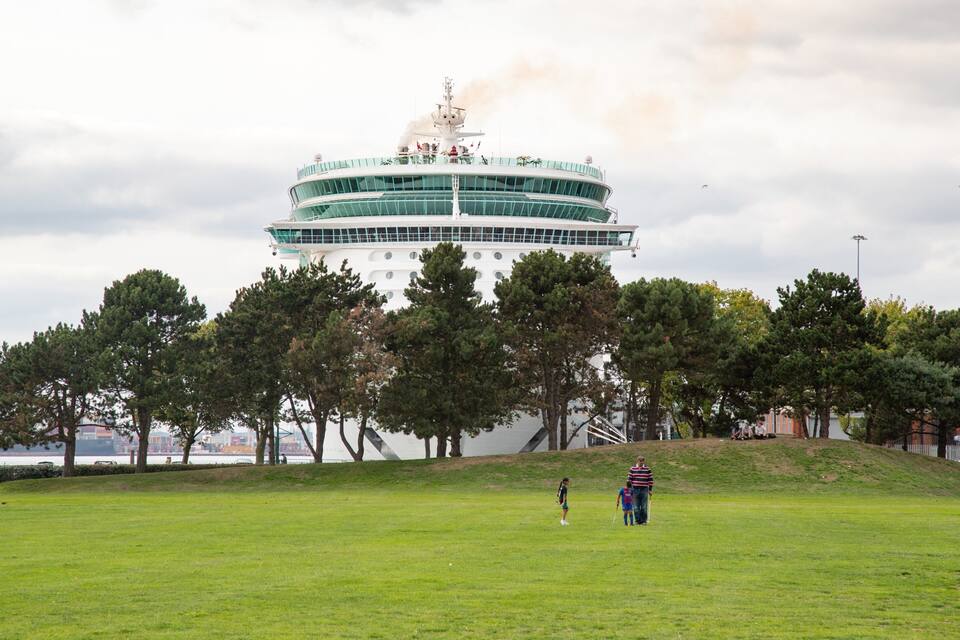 A grassy field with a large white building with a circular top and a tower.