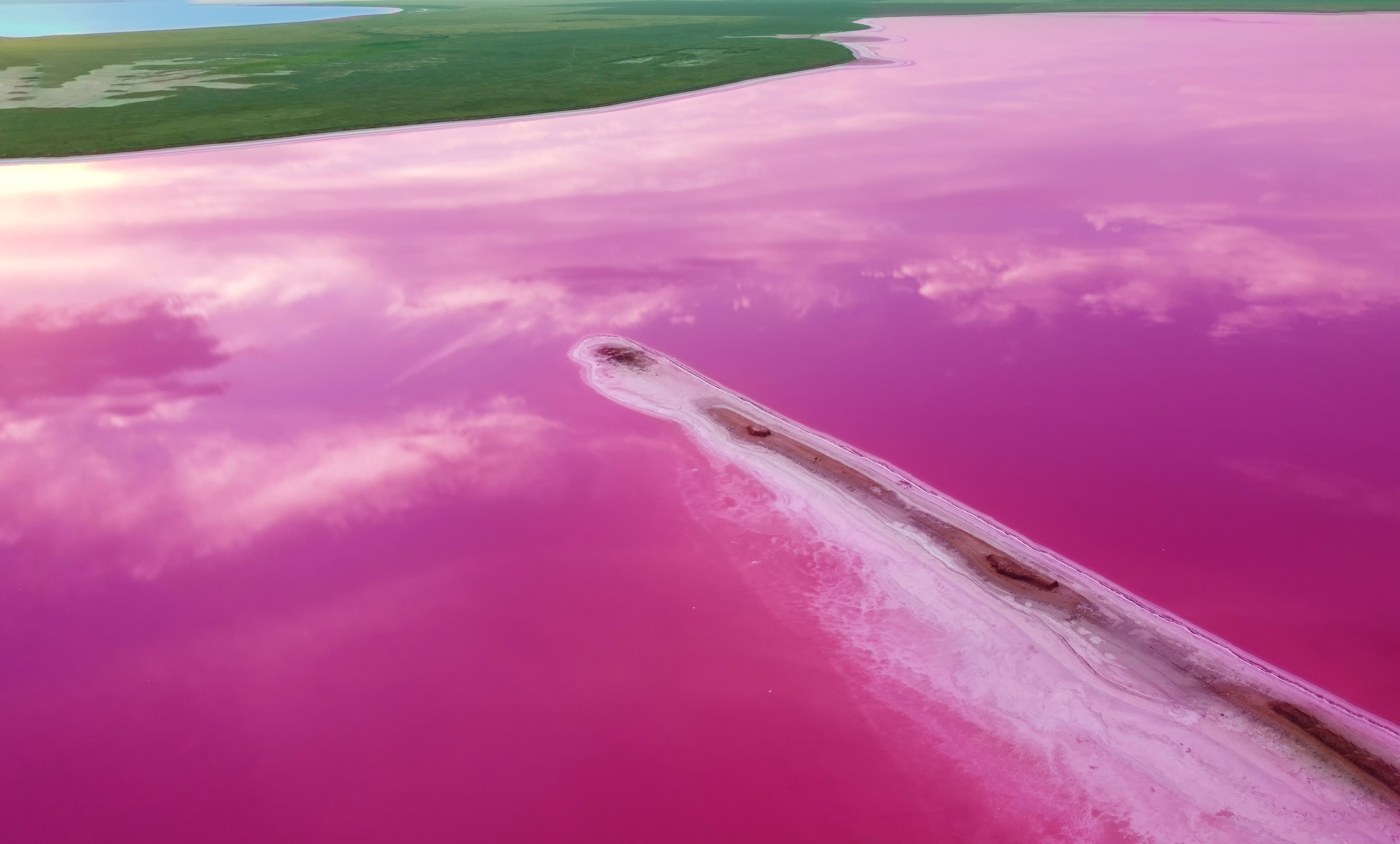 Aerial view of a pink lake and an elongated island of salt and sand. Therapeutic salt lakes with healing properties