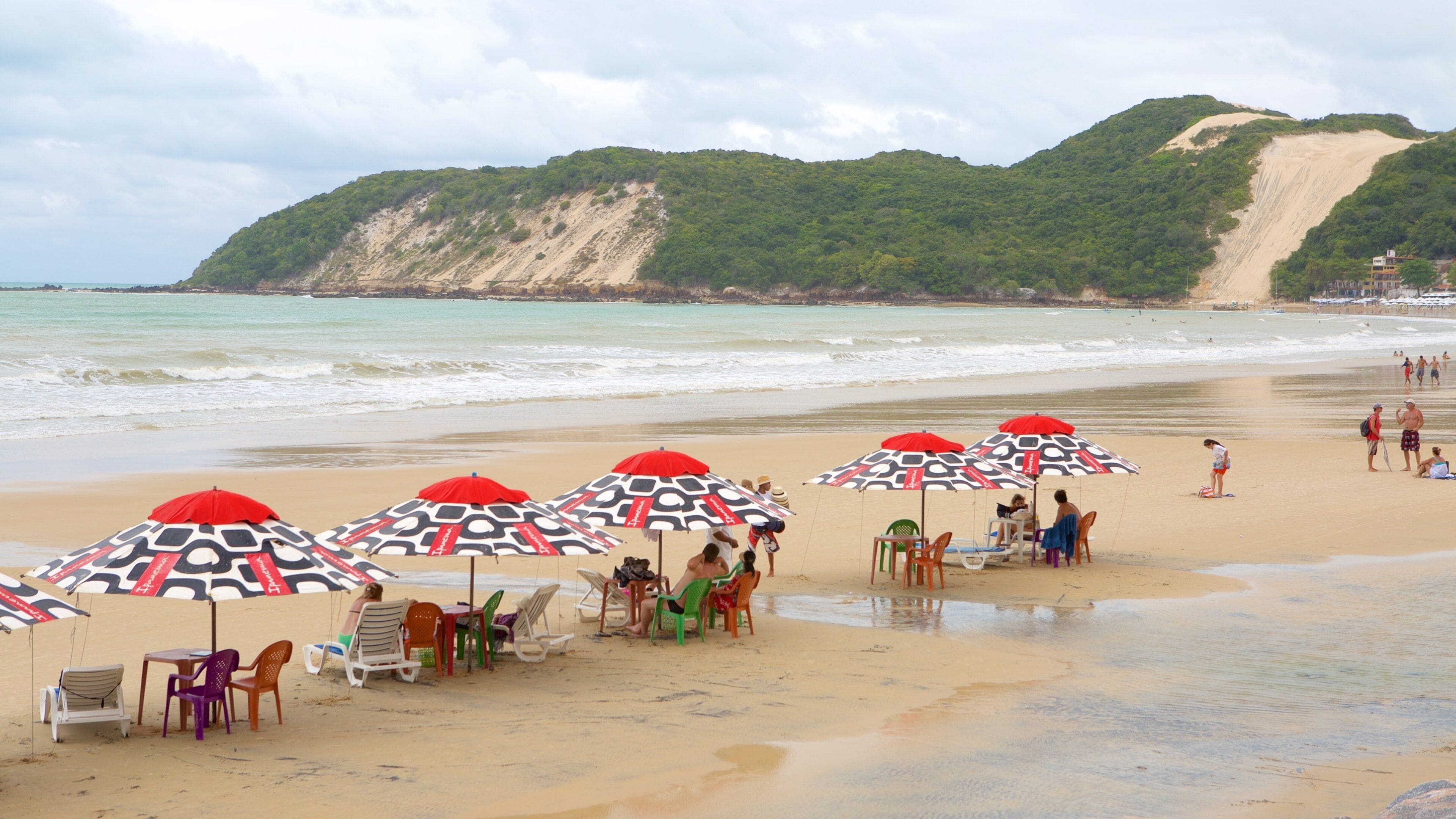 A beach with umbrellas, chairs, and people.