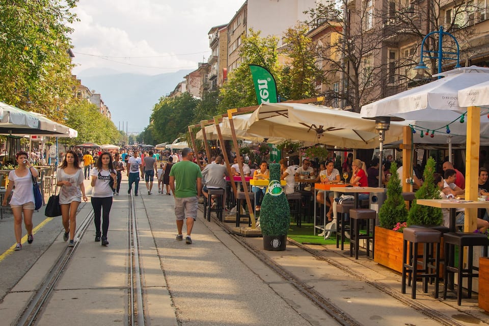 A busy outdoor market with people walking and dining.