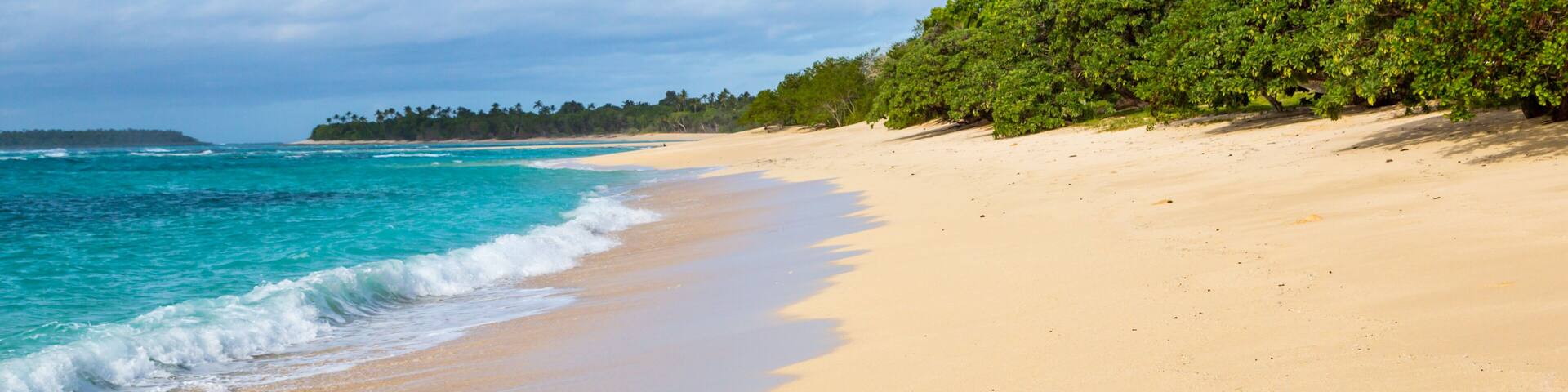 Shore of an azure, turquoise, blue lagoon. Waves, surf, swash at a remote empty idyllic sandy beach on Foa island, Haapai (Haʻapai or Ha'apai) group, Tonga, Oceania, South Pacific Ocean. Near Lifuka.