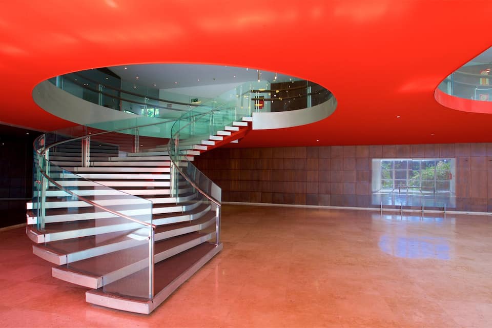 A modern interior with a spiral staircase, red walls, and a glass ceiling.