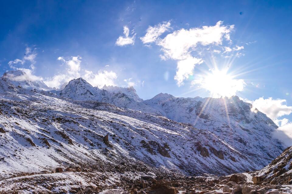 Una cordillera nevada con cielo despejado y luz solar.