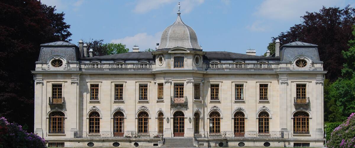 A large, historic building with a central dome, symmetrical windows, and a formal entrance.