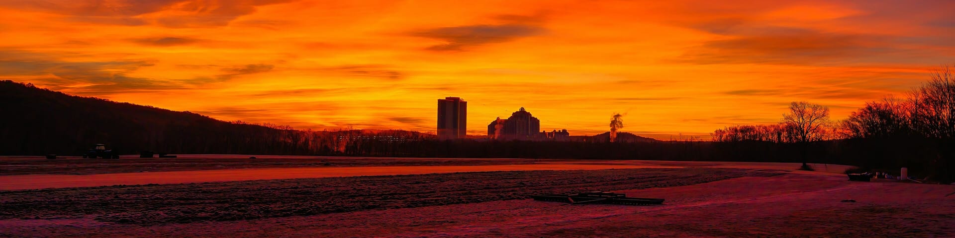 A sunset over a river with buildings in the distance.
