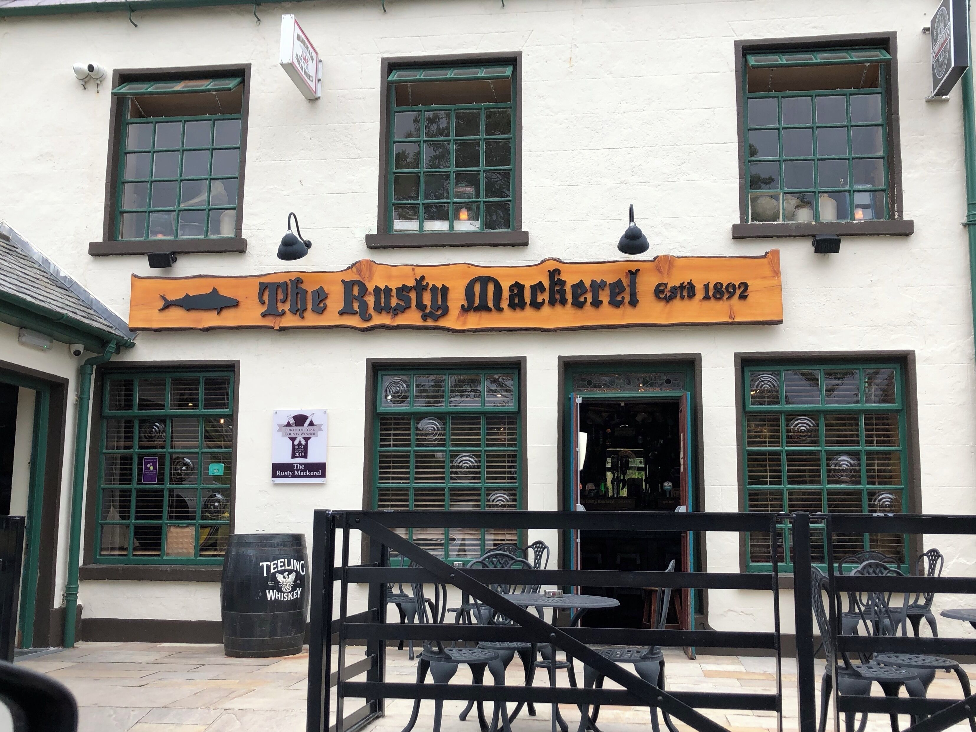 The Rusty Mackerel pub with a signboard, multiple windows, and outdoor seating.