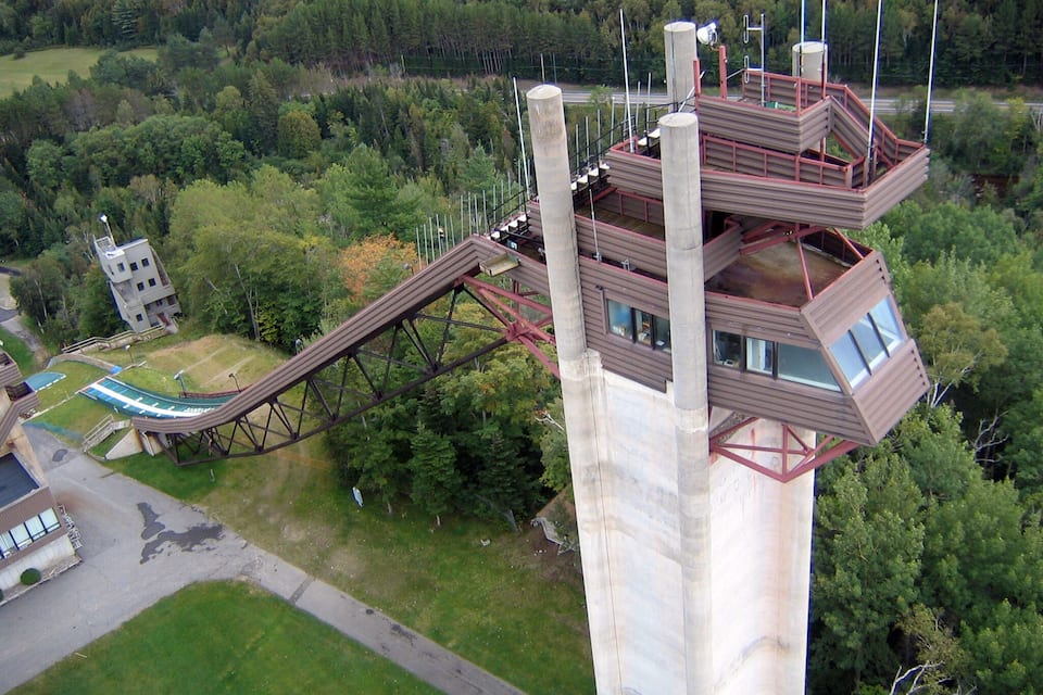 A tall tower with a roller coaster, surrounded by dense forest.